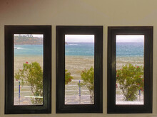 View Through Three Windows Of The Rough Sea And Wet Shrubs.