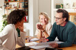 © ALTO IMAGES/Stocksy - Smiling couple discussing home finance with financial advisor at home