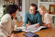 © ALTO IMAGES/Stocksy - Happy couple having finance discussion with consultant at home
