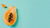 A halved papaya on a blue background. The papaya is orange and has black seeds. The papaya is cut in half and you can see the seeds inside.