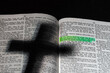 An open bible with a shadow of a cross and a highlighted verse.