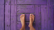 A photo of beautiful female feet with great toes standing on an old purple wooden floor