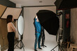 © Ezequiel Giménez/Stocksy - Woman watching photographer adjusting light in studio