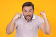 Man shouting. Portrait of Angry man screaming. Portrait of young shouting man isolated on yellow background. Shouting male face. Guy shouting with nervous crisis. Negative human emotions.