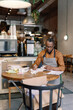 © Oleksii Syrotkin/Stocksy - Barista working on numbers