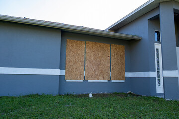 Wall Mural - Plywood mounted as storm shutters for hurricane protection of house windows. Protective measures before natural disaster in Florida