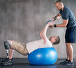© peopleimages.com - Physiotherapist, person with a disability and prosthetic leg and dumbbell in physiotherapy, studio and gym ball. Male people, trainer and amputee for wellness, fitness and exercise in workout session