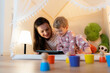 © Santi Nuñez/Stocksy - happy mother and son playing at home in tent