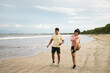© Pedro Merino/Stocksy - Asian friends on the beach in sportswear