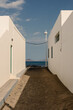 © Adrian Rodd/Stocksy - View of the sea from an alley between two white buildings