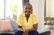 African American senior woman sitting at home, wearing a yellow shirt and jeans