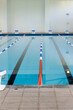 Empty swimming pool lanes indoors await swimmers, marked by colorful lane dividers, copy space