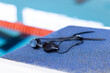 Swimming goggles resting on edge of indoor pool, close-up view, copy space