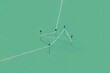 © Yaroslav Danylchenko/Stocksy - Several stationery pins stuck in green paper and tied with thread