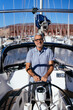 © Alberto Rojas/Stocksy - Cheerful captain standing behind steering wheel of cruising yacht