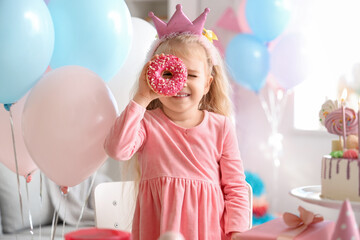 Wall Mural - Cute little girl in crown with doughnut celebrating Birthday at home