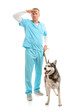 Male veterinarian with cute husky dog looking somewhere far on white background