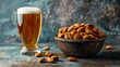   A blue tablecloth features a textured background, upon which sits a bowl of almonds and a glass of beer