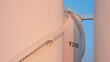 Curve lines pattern of spiral staircase on group of white storage fuel tanks with orange sunlight on surface against blue evening sky background