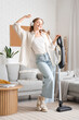 © Pixel-Shot - Happy young woman in headphones with vacuum cleaner dancing at home