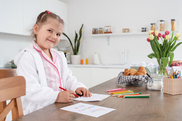 Wall Mural - Cute little girl drawing greeting card to Mothers Day at table in kitchen