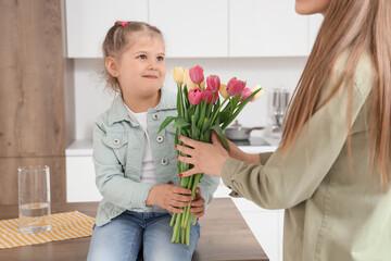 Sticker - Little girl sitting on table and greeting her mom with Mothers Day in kitchen