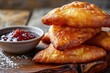 Beignets on a wooden cutting board, with a small bowl of raspberry jam