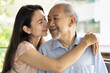 Senior Father and Middle aged Daughter smiling together in positive expression, Happy Asian family with daughters cheek kissing old father, concept of Happy Father’s Day, Family Togetherness
