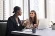 © fizkes - Serious diverse business colleagues meeting in coworking cafe, talking at laptop, discussing work project. Young businesswoman consulting African advisor, legal expert, agent