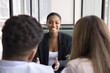 © fizkes - Happy African American real estate consultant meeting with young couple at table in cafe, speaking, smiling, discussing property buying, mortgage. Legal financial advisor giving consultation