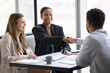 © fizkes - Happy multiethnic business male and female partners shaking hands over table, buying and selling startup, celebrating hiring, employment, partnership, investment, giving handshake