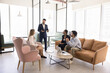 © fizkes - Multiethnic small business team and Indian male boss meeting in modern co-working space, sitting on soft couch, listening to speaking leader, discussing project strategy