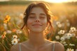 A cheerful young woman enjoying the sunset in a field of daisy flowers