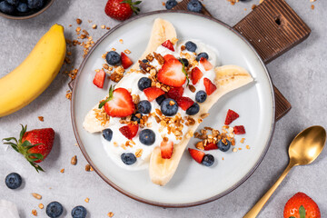 Wall Mural - Healthy Banana Split Breakfast with Yogurt, Granola and Fresh Berries