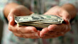 close-up shot of a person's hands holding a stack of cash,