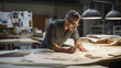 © arnaud - Un architecte examine des plans sur une grande table de travail dans un bureau moderne et bien éclairé. Il porte des lunettes et une chemise à manches longues, penché sur un rouleau de dessins d'archi