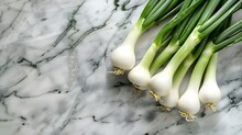 A Leek Lies On The White Marble Countertop