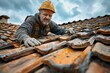 A focused construction worker replaces damaged roof tiles with skill and experience