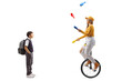 Surprised schoolboy standing and watching a female riding a mono cycle and juggling
