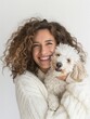 Happy woman in a cozy sweater hugging her fluffy white dog, sharing a moment of joy.
