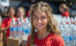 Young girl smiles at the camera while other volunteers stand behind her with water bottles.