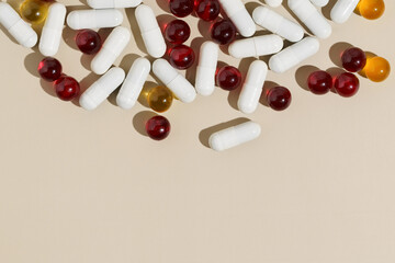 top view of red, yellow and white capsule pills on beige isolated background. place for your design.