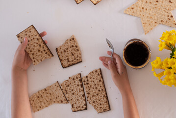 Wall Mural - hands of girl hold matzo make sandwich with chocolate. traditional and kosher food for passover. Traditional of Jewish Holiday on Passover. 