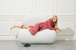 Playful lazy woman in pink pyjamas reclining on a soft ottoman