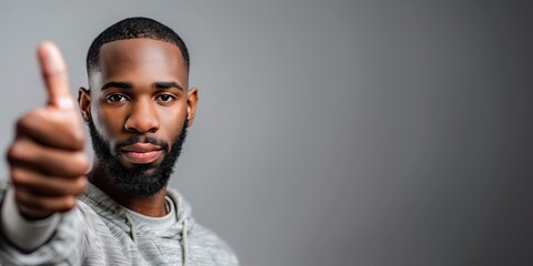 A 25 year old man raises his hand and shows a thumbs up on a white background