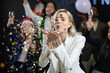 © NVB Stocker - confetti. Hppy caucasian woman blowing multicolor confetti. Business Party and new year's eve with diverse business people