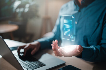 Poster - document, file, future, job, management, marketing, occupation, paperwork, strategy, information. A man is holding a piece of paper in front of a laptop. Concept of a document being created or edited.