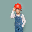 Little girl worker in a safety helmet with a tool on a blue background.
