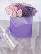 A roll of transparent packaging film and a bouquet of roses in a box on the table