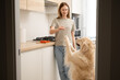 Young woman in the kitchen drinking juice with her dog. A happy girl strokes her dog before breakfast